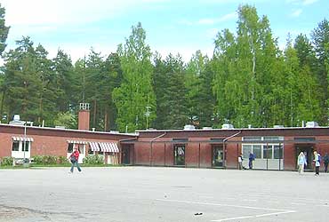Årsunda kyrkskola är en byggnad i ett plan med tegelfasad. Framför skolan syns en stor plan och bakom skolan en skog.