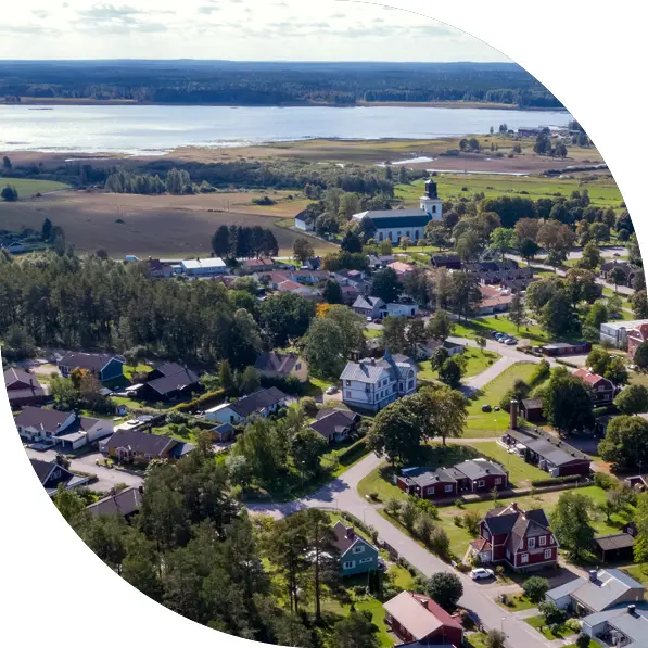 Drönarbild över Årsunda visar bebyggelse, kyrka och vatten. Foto.
