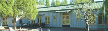 Bullerbyns förskola en en enplanshus med blåmålad fasad. Flera träd syns runt huset.
