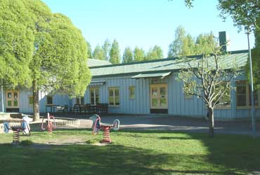 Bullerbyns förskola en en enplanshus med blåmålad fasad. Flera träd syns runt huset.