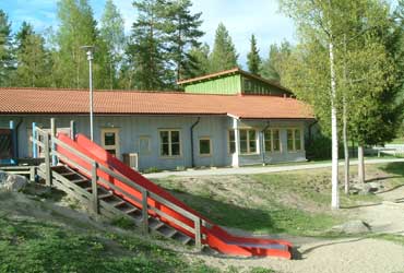 Fäbogårdens förskola är en enplanshus med blå fasad. Runt förskolan finns flera träd