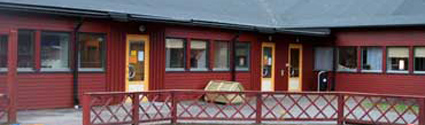 Kyrkåsens förskola ligger i en enplansfastighet med röd fasad och gula dörrar