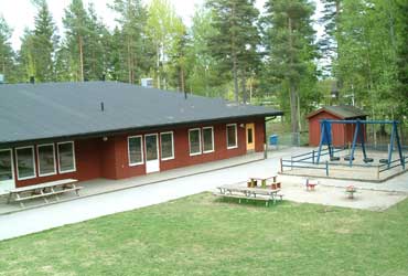 Rödmålat enplanshus med lekredskap vid Smassens förskola