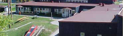 Smultronbackens förskola ligger i ett hus med röd fasad och rött tak. På gården är en grön gräsmatta och lekredskap
