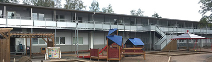 Gråvita byggnader som är en del av Sätralinjens förskola. Framför huset finns lekredskap