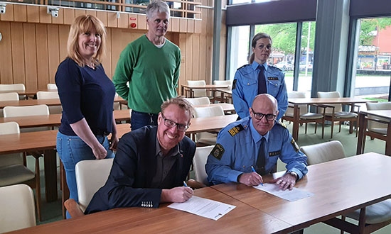 Peter Kärnström och lokalpolisområdesschef Lars Jansson sitter vid ett bord och skriver under två papper.
