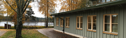 Alsjöskolan ligger i en grönmålad enplansfastighet. I bakgrunden syns sjön och träd med höstfärger