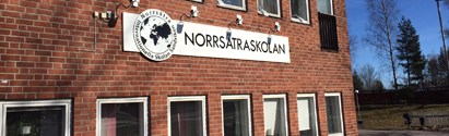 Skylt med texten Norrsätraskolan på en röd tegelbyggnad