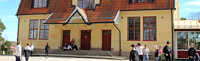 Västanbyskolans gula byggnad med rött tak. På skolgården framför skolan syns elever