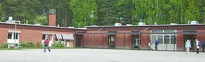 Årsunda kyrkskolas röda tegelbyggnad med skog bakom