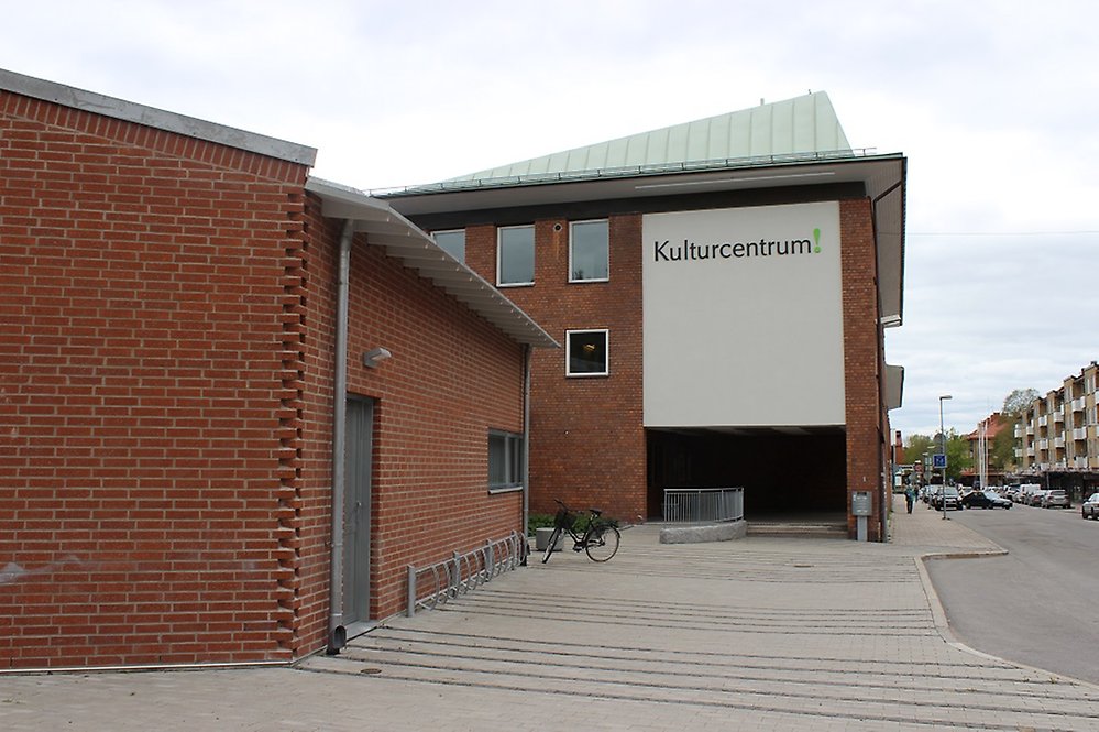 Byggnad med röd tegelfasad och en skylt på väggen med texten Kulturcentrum. Byggnaden ligger vid en gata.